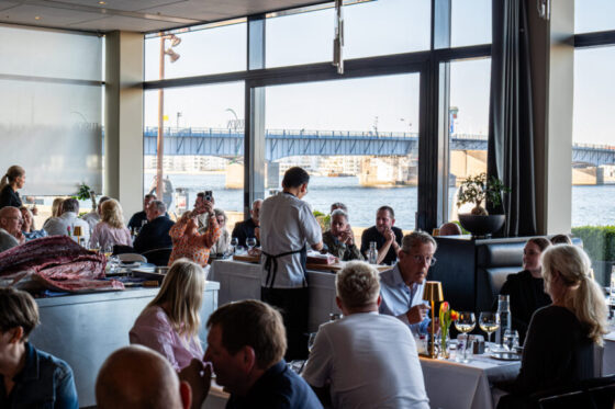 Gæster spiser på restaurant med udsigt til havnebro