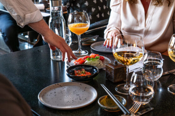 Gæster deler sushi og vin ved restaurantbord