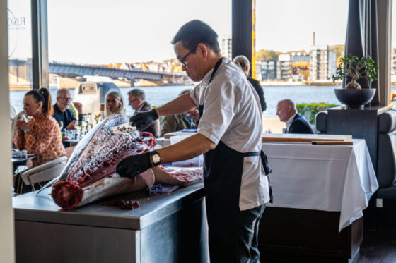 Kok fileterer stor tun på restaurant ved vandet